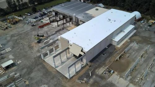Aerial view of an industrial building under construction with materials and equipment scattered around.