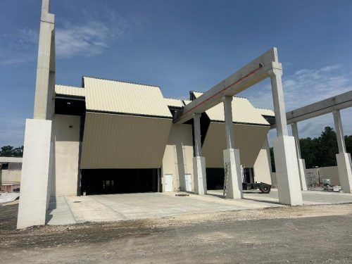 A spacious warehouse featuring two large doors and a prominent building structure.