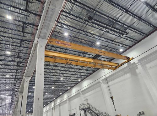 A large overhead crane positioned in a warehouse, ready to lift heavy materials for storage or transport.