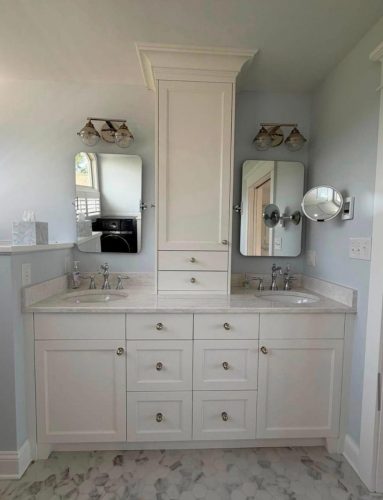 Double sink vanity with white cabinets, marble floor, two mirrors, and wall-mounted lights in a bathroom.